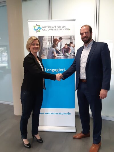 Andeas von Bismarck, chairman of the association Wirtschaft für ein weltoffenes Sachsen (right) welcomes Siltronic AG, represented by Ines Richter from the Freiberg plant's communication department, as a new member of the association. 